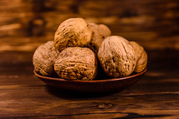 Ceramic plate with walnuts on a wooden table