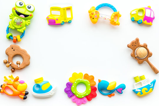 Handmade toys for newborn babies, plastic and wooden rattle on white background top view copy space frame