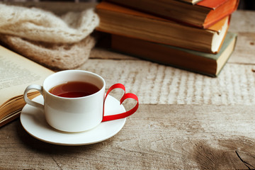 Love of books, reading. Stack of books on the wooden table.and origami paper craft the shape of a heart, cup of tea. Library, education, leisure time concept.