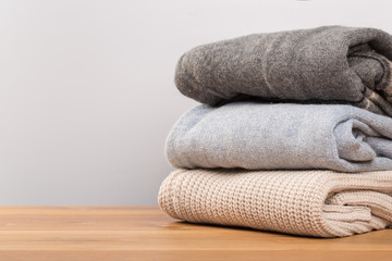 different sweaters on a wooden table on a light background. Autumn and winter clothes.