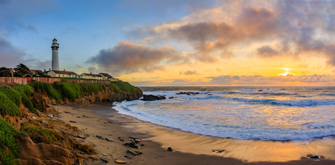 Pastel colors of sunset and silky water from long exposure of waves crashing by Pigeon Point Lighthouse on Northern California Pacific Ocean coastline at sunset