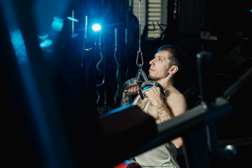 Handsome athletic man working out on the gym machine in the gym.