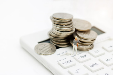 Miniature people: Businesswoman standing on calculator with coins stack, Retirement planning, Emergency plan, Life insurance and Financial Concept.