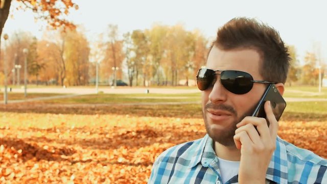 bearded man talking on the smartphone and smoking an e-cigarette