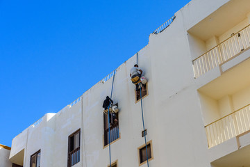 Fototapeta na wymiar Rope access workers on a residential building in Hurghada, Egypt