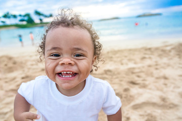 Adorable cute smiling mixed race little boy playing and having fun on a beach vacation. Close up view of his happy expression