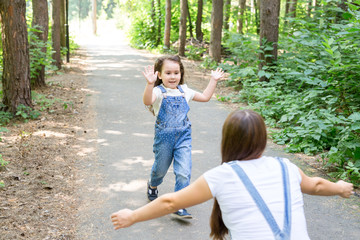 Nature, family, people concept - Adorable little kid girl and young woman in beautiful forest. Daughter running to mother