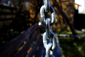 The element of the metal chain, as a decoration to the swings in the territory of the house for the rest. Metal chain on the street swing in the background of the cottage for tourists. 