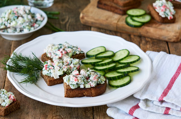 Sandwiches with cucumbers, crab sticks and greens on a plate
