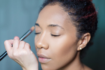 professional make-up makeup artist apply makeup to a dark-skinned woman