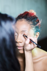 professional make-up makeup artist apply makeup to a dark-skinned woman