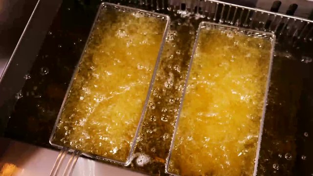Unhealthy French fries boiling in fresh oil at the bistro pov