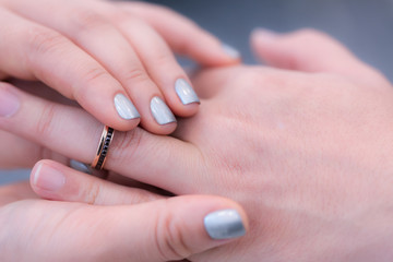 Wedding theme, Bride putting ring on groom hand, and they holding hands with a nice manicure neat. Close up hands of man and woman put wedding ring on hand.