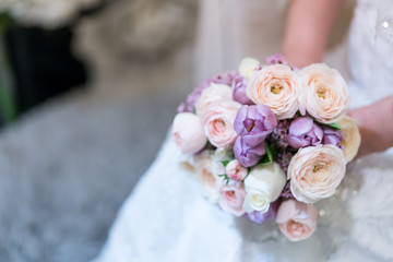  Bride holds a wedding bouquet. Very nice young woman in a white wedding dress holding a beautiful blossoming flower bouquet of various kinds of fresh real flowers, in pink, red and pastel cream color