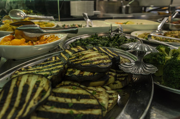 Fried eggplants, broccoli and salads in plates in the kitchen