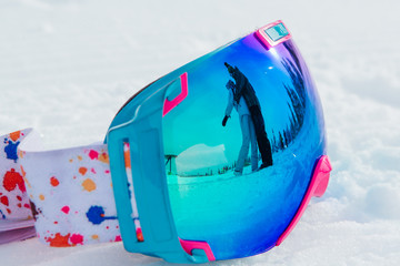 Close-up of ski and snowboard mask with reflection of inloved couple hugging