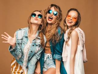 Foto auf Acrylglas Three beautiful smiling hipster girls in trendy summer casual clothes and sunglasses. Sexy carefree women posing near golden wall. Positive models going crazy. Showing tongue © halayalex