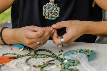 Artist making custom turqoise jewelry at art fair.