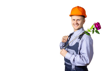 A cheerful smiling man builder on a white background with a rose in his hands congratulates everyone on the holiday. World Women's Day, March 8, the day of celebration, anniversary, holiday. Isolated