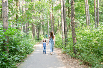 Family, nature, people concept - Mom and daughter spend time together on a walk in the summer forest