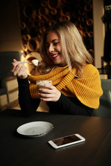 Smiling beautiful girl in cafe or restaurant drinking cappuccino or latte.