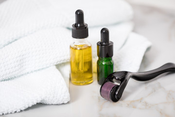 Dermaroller, Handtuch, gelbe Pflege Öl und grüne Serum Flaschen zum  Microneedling für Anti...