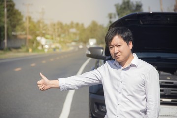 Man raising their hands for help because his car is broken.