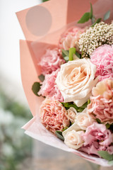 beautiful fresh cut bouquet of mixed flowers in vase on wooden table. The work of the florist at a flower shop. Delicate Pastel tones color