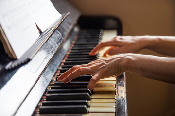 Fototapeta na wymiar Close up fingers of woman pianist at the rusty piano keys, arms plays solo of music. Hands of female musician playing. Music instrument, solo pianist, song composer, hobby, practice study.