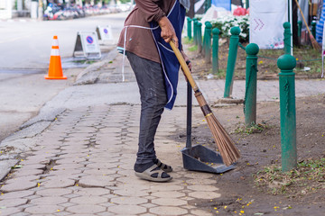 Young woman swept garbage by broom.