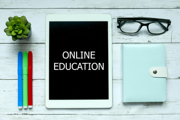 Obraz premium Education and business concept. Top view of colorful pen,plant,glasses,notebook and tablet pc written with Online Education on white wooden background.