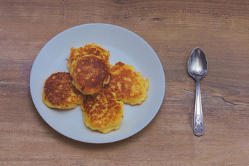 4 curds patty and spoon and white plate on wooden background.