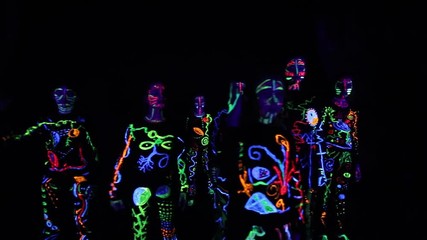 group of children performs performances in a dark hall, in colorful costumes. Paint in costumes shines in the dark. Choreographic setting of a group of children