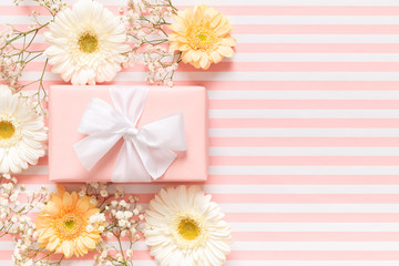 Happy Mother's Day, Women's Day, Valentine's Day or Birthday Pastel Pink Background. Floral flat lay greeting card with beautifuly wrapped present and gerbera flowers.