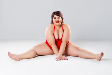 Fototapeta premium Plus size fashion model in red lingerie, fat woman in underwear on gray studio background, overweight female body