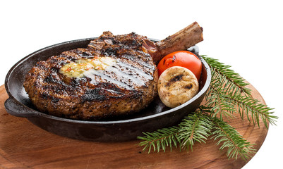 Cowboy beef steak in a cast iron pan on a wooden board