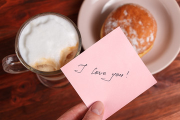Cappuccino mug, cake and notes I love you on a wooden background. Concept Valentine Day