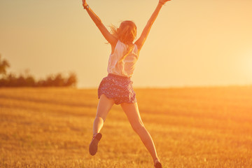 Obraz premium Cute young woman jumping in a wheat field.