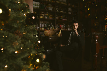 Attractive man wearing black tuxedo in whiskey bar.