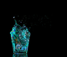 colorful cocktail in glass with splashes on dark background. Party club entertainment. Mixed light