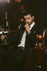 Attractive man wearing black tuxedo in whiskey bar.