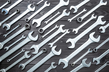 set of chromed wrenches on a dark wooden workbench. top view