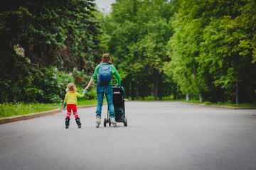 Obraz premium active family- mother and little girl on roller skates with stroller in city