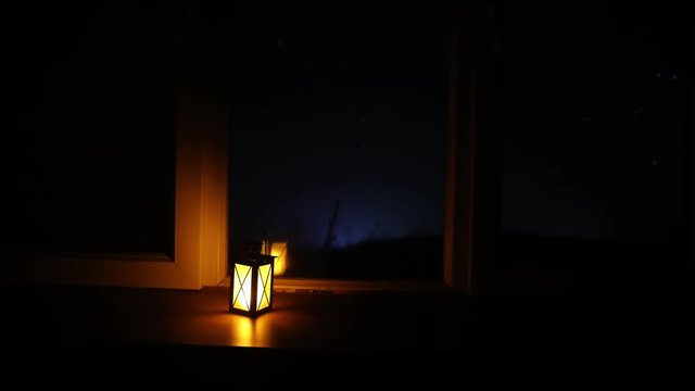 Night scene of stars seen through the window from dark room. Night sky inside dark room viewing from window with old vintage lantern. Long exposure shot