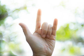 Love with the finger symbol Green tree bokeh as background.soft focus.