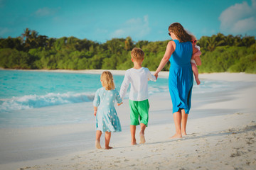 mother with three kids walk on beach