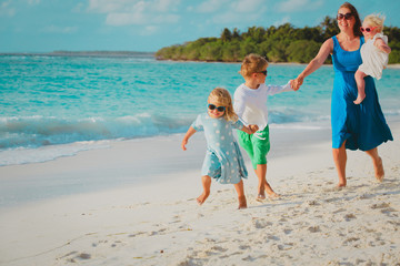 Naklejka premium mother with kids play run on tropical beach