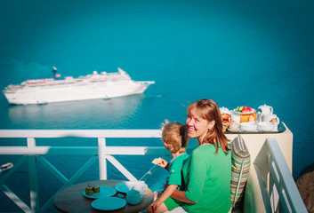 happy mother and little son looking at cruise ship at sea, having breakfast