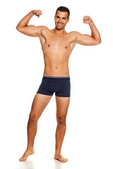 Fototapeta premium Shirtless handsome smiling man in panties on white background showing his biceps