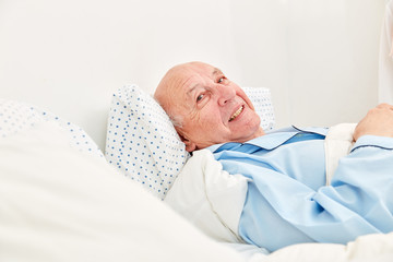 Senior liegt krank im Bett als Patient